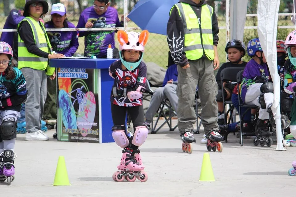 Una niña del equipo patina junto a los conos y la zona de acompañantes.